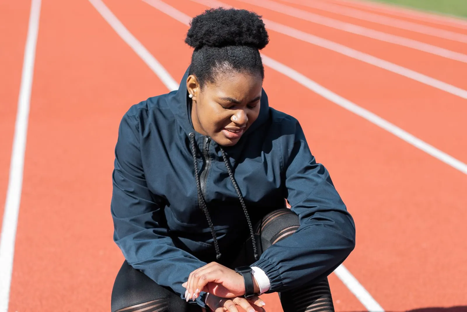 Corredora conferindo o relógio de corrida na pista de atletismo