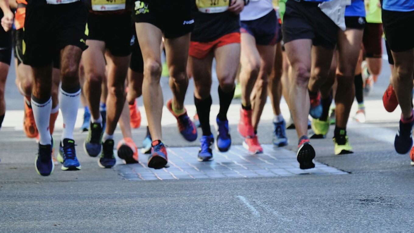 Pernas e tênis de corredores em uma corrida de rua no asfalto